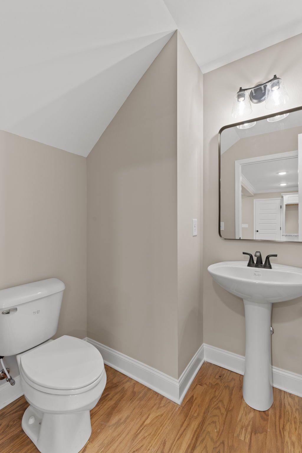 A bathroom with a toilet , sink and mirror.