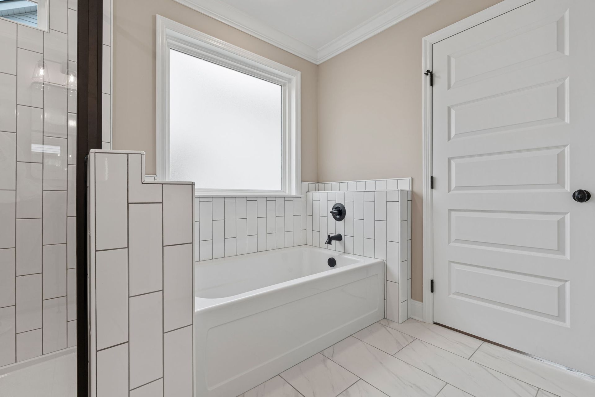 A bathroom with a tub , shower , and window.