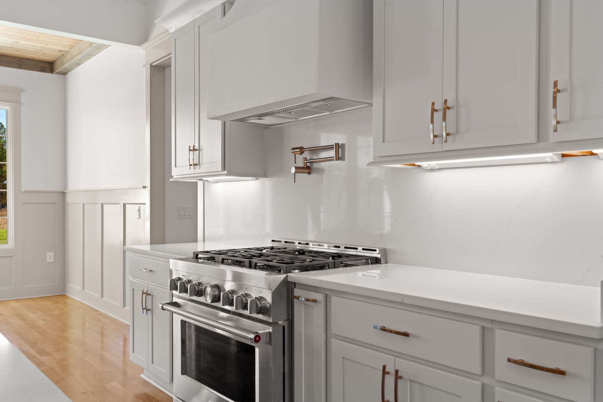 Bright modern kitchen with gray cabinets, white countertops, and stainless steel stove.
