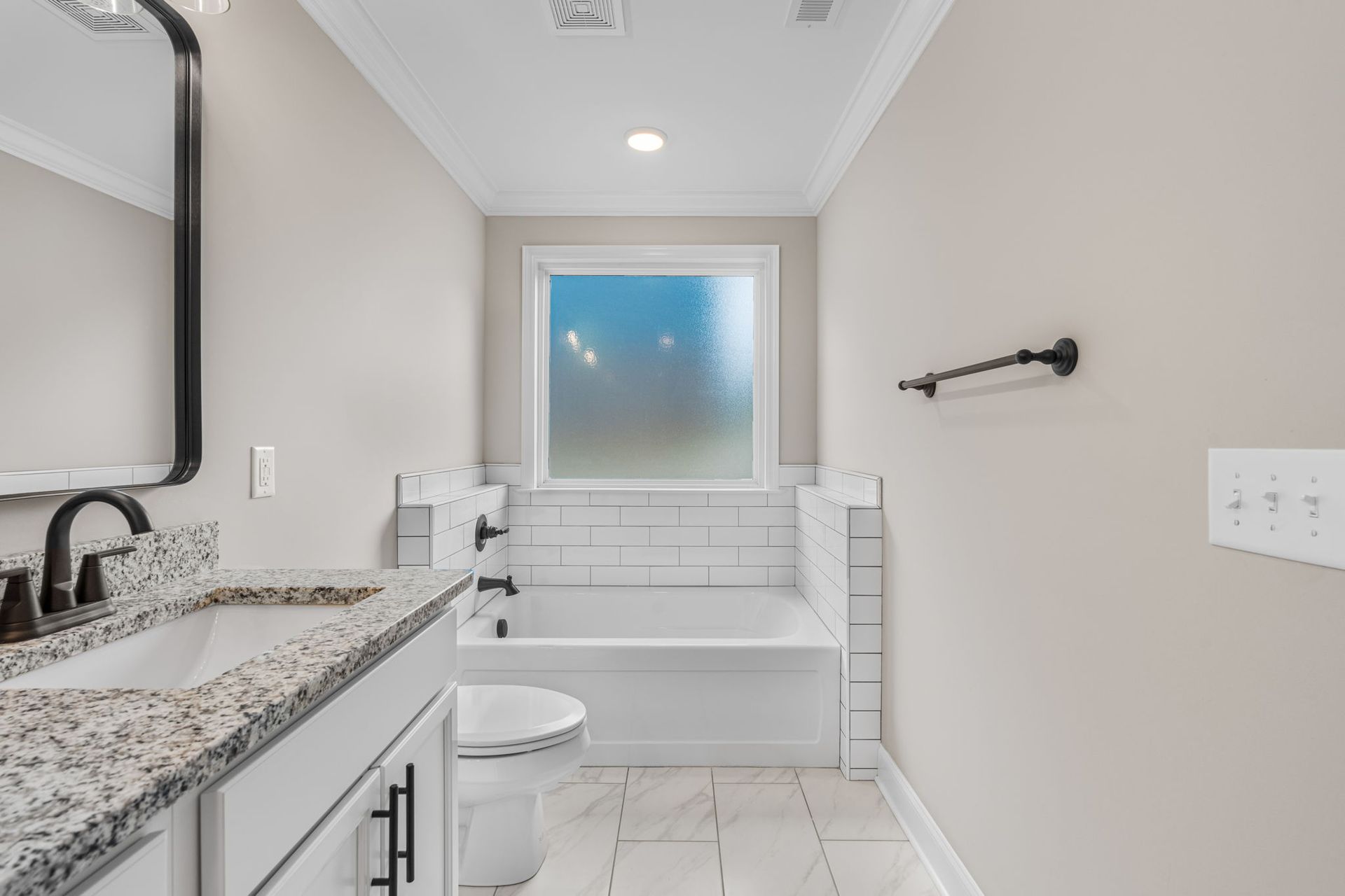 A bathroom with a sink , toilet , tub and window.