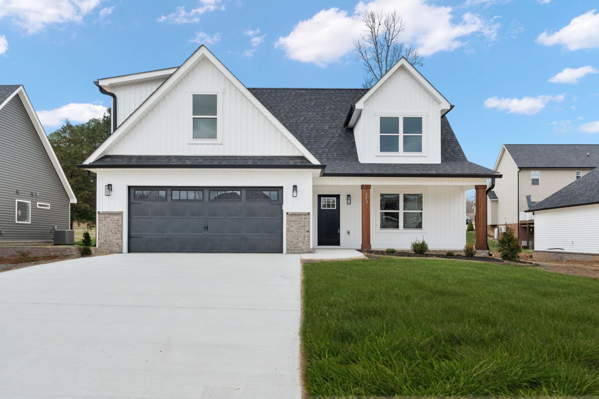 A white house with a black garage door is for sale.