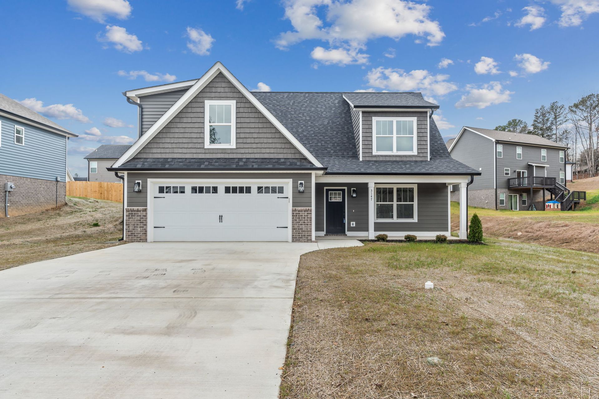 A large gray house with a white garage door is for sale.