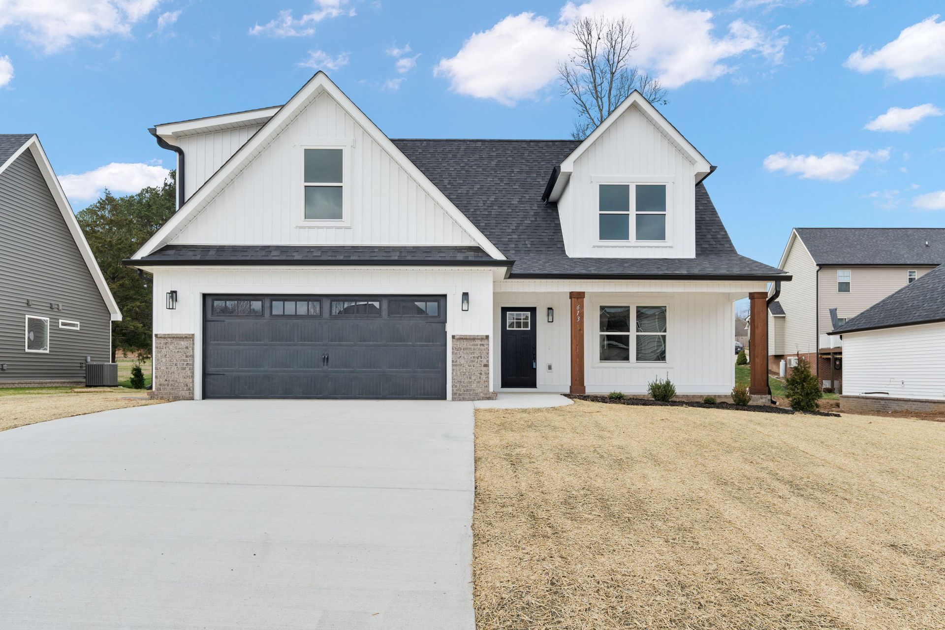 A white house with a black garage door is for sale.