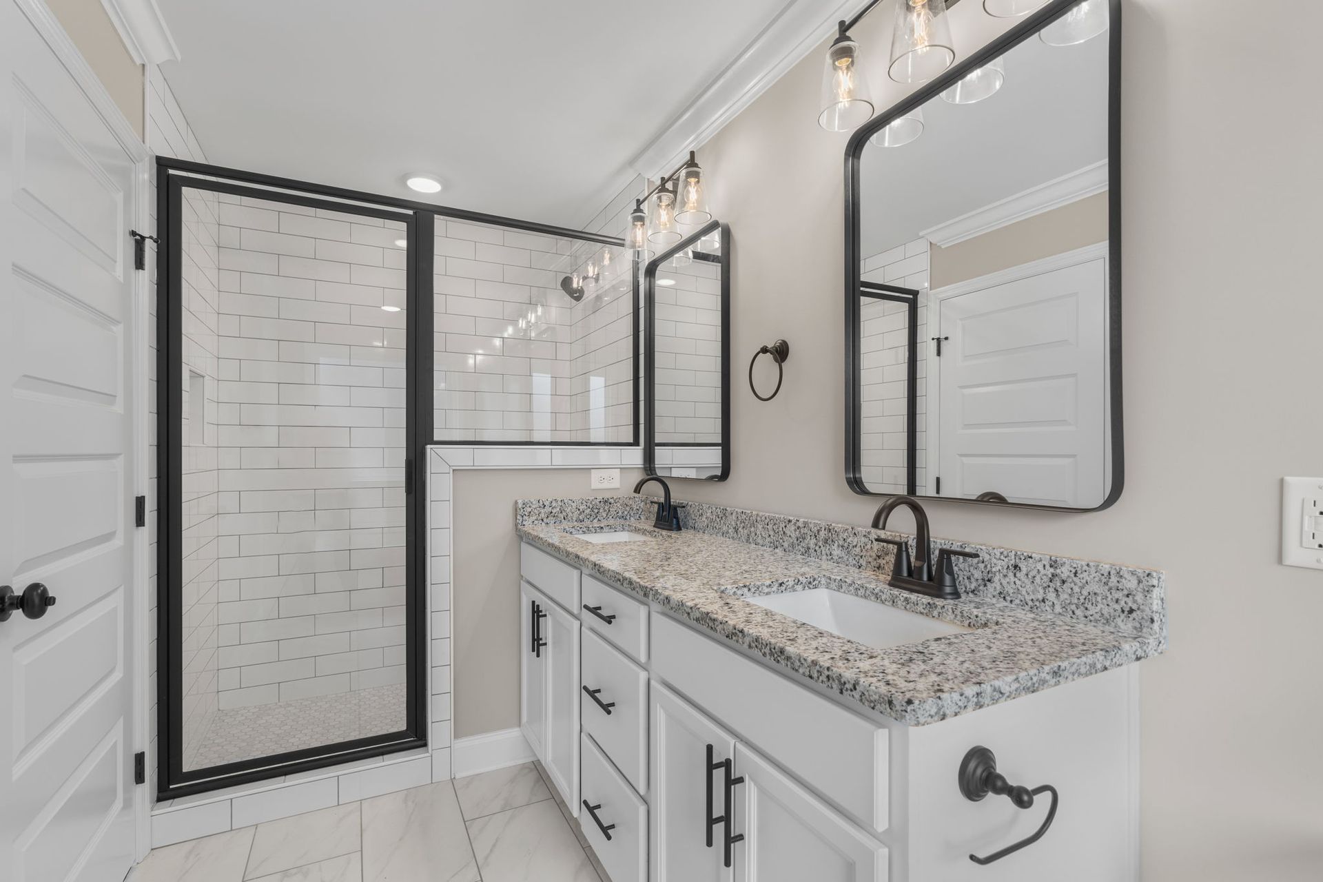 A bathroom with a sink , mirrors and a walk in shower.