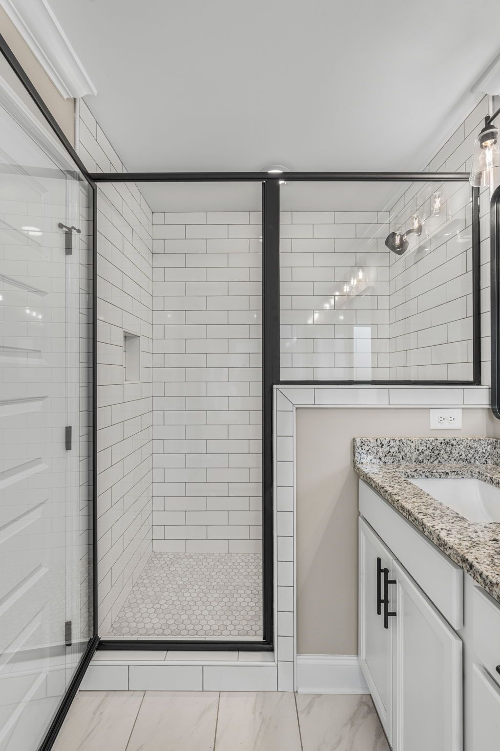 A bathroom with a walk in shower and a sink.