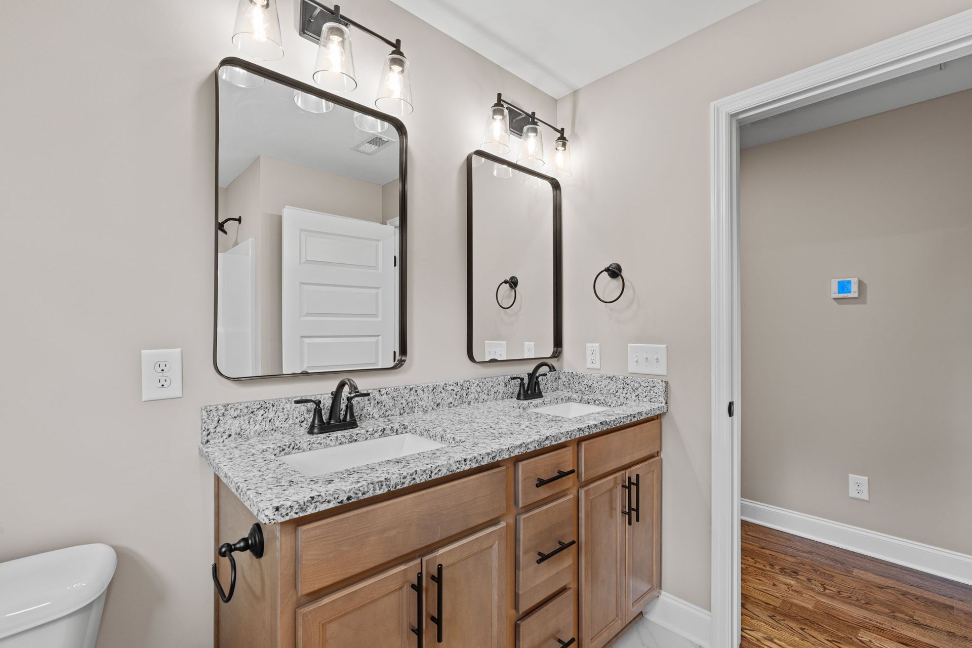A bathroom with two sinks , two mirrors and a toilet.