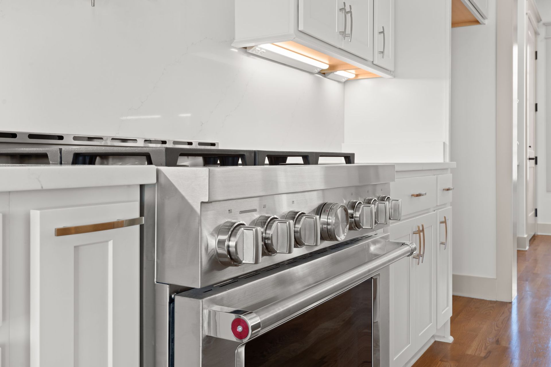 Modern kitchen with stainless steel gas range, white cabinets, and hardwood floor