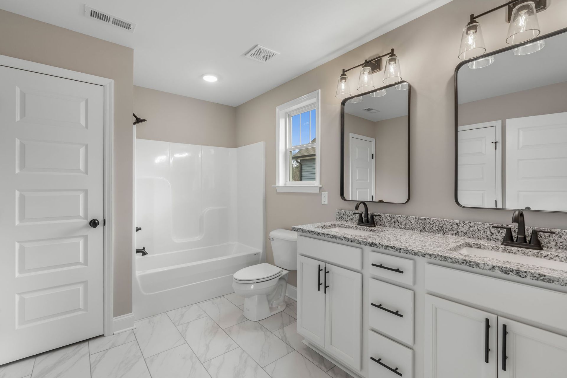 A bathroom with two sinks , a toilet , and a window.