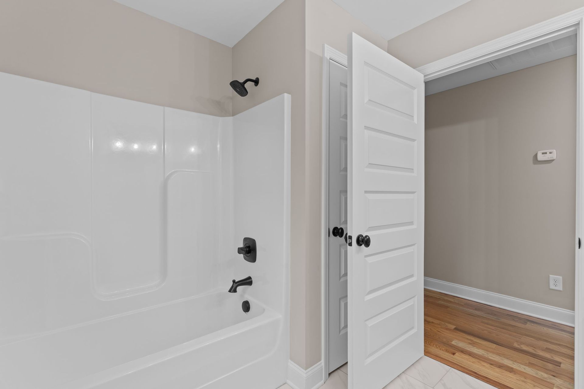 A bathroom with a tub , shower , and door.