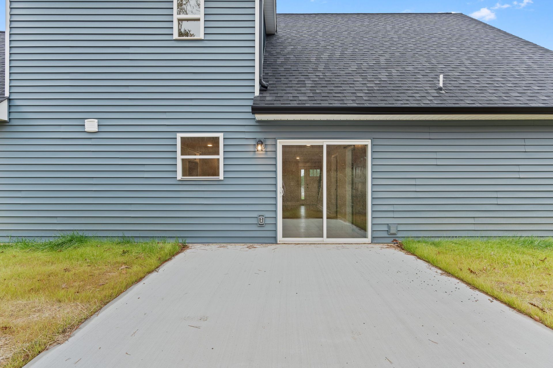 The back of a house with a patio and sliding glass doors.