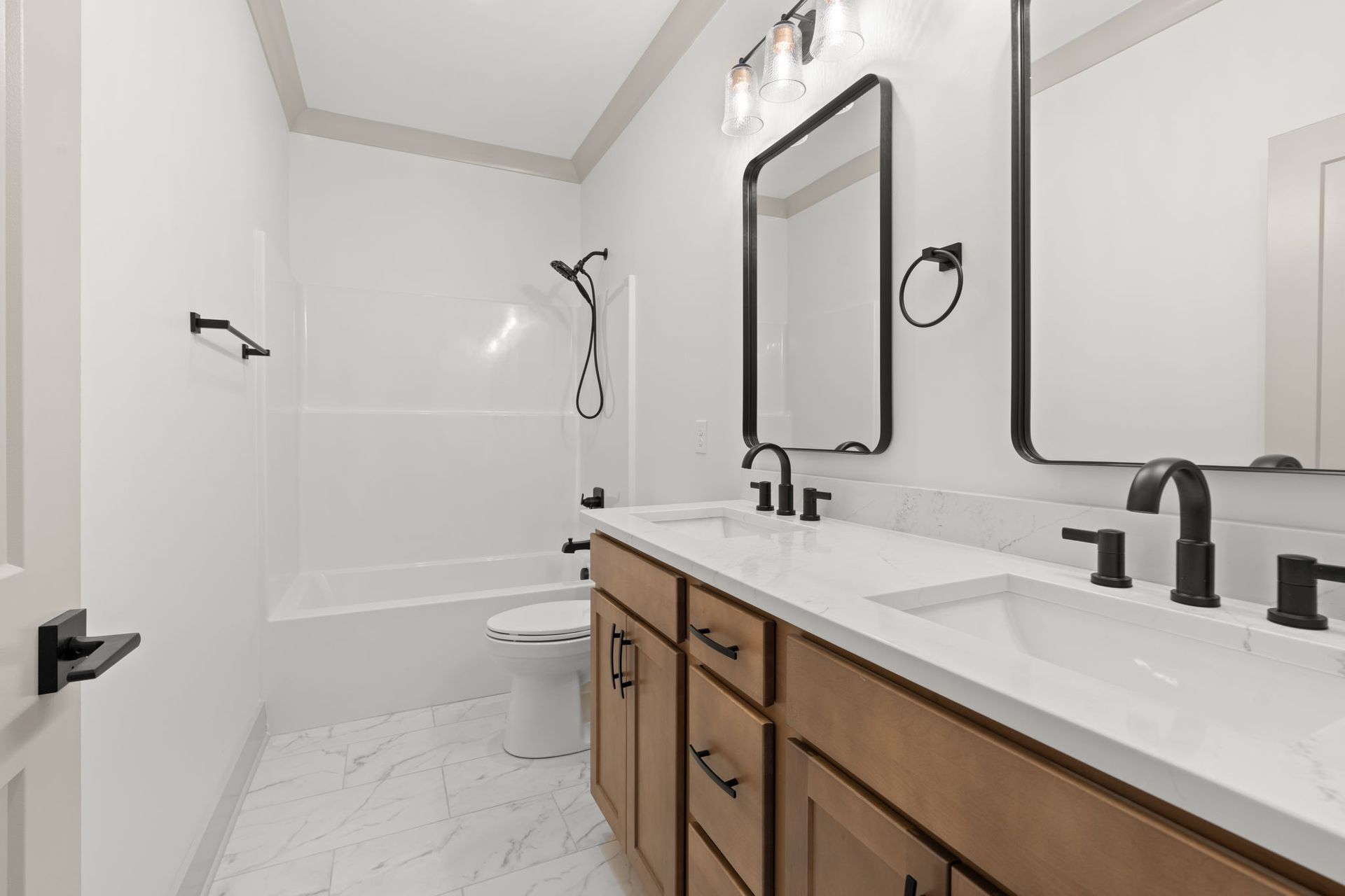 Bright modern bathroom with white tub, wood vanity, black fixtures, and large mirror.