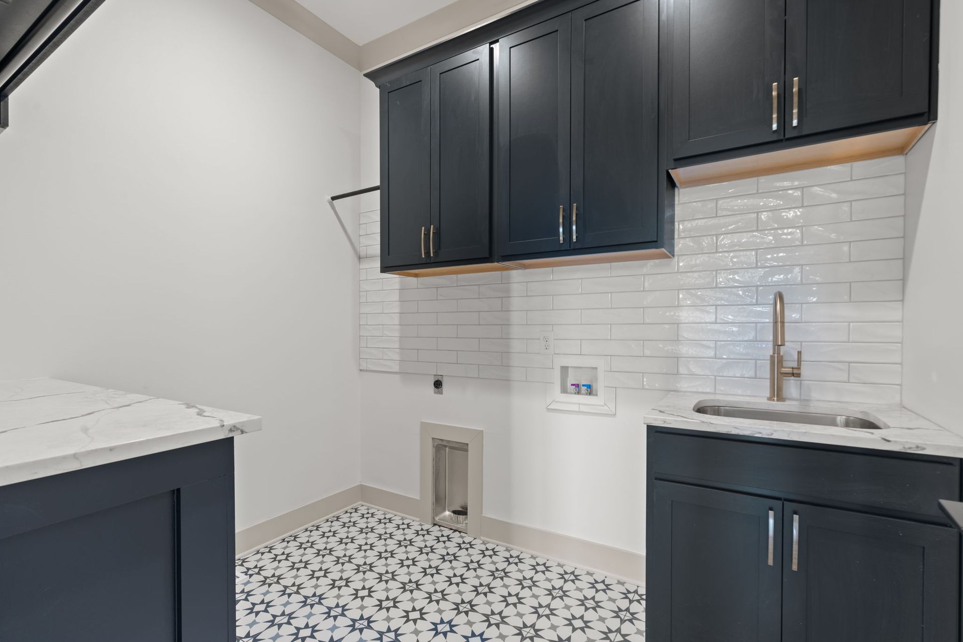 Modern kitchen with dark cabinets, white countertops, white subway tile, and patterned floor tiles