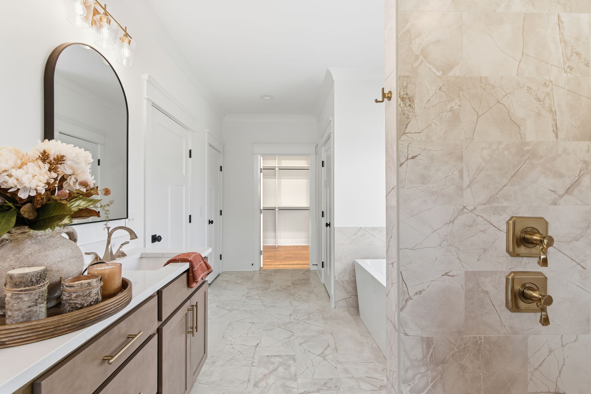 Bright hallway with marble flooring, console table decor, and a marble bathroom doorway on the right