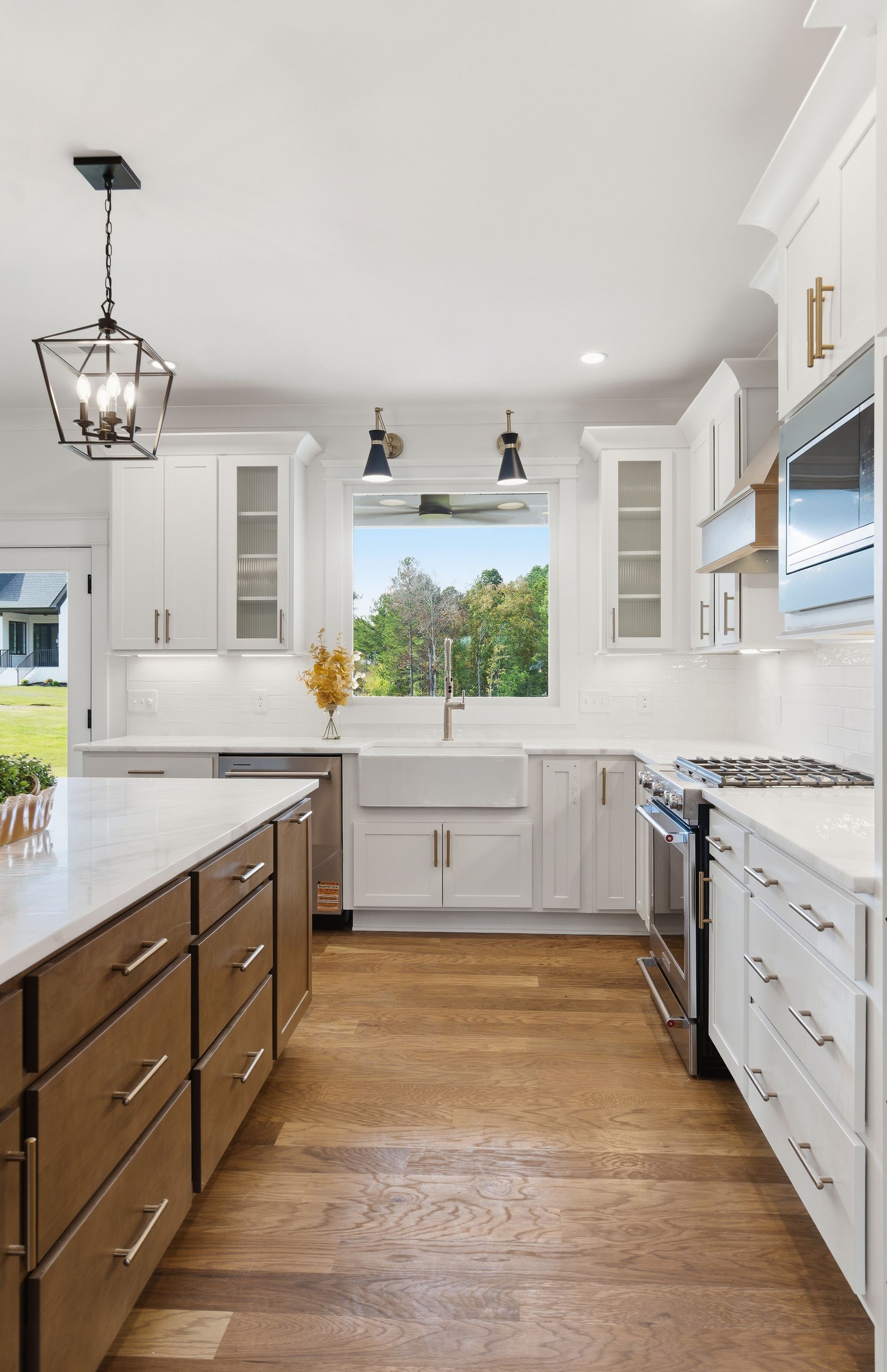 Bright white kitchen with dark island, wood floor, and a window over the sink.