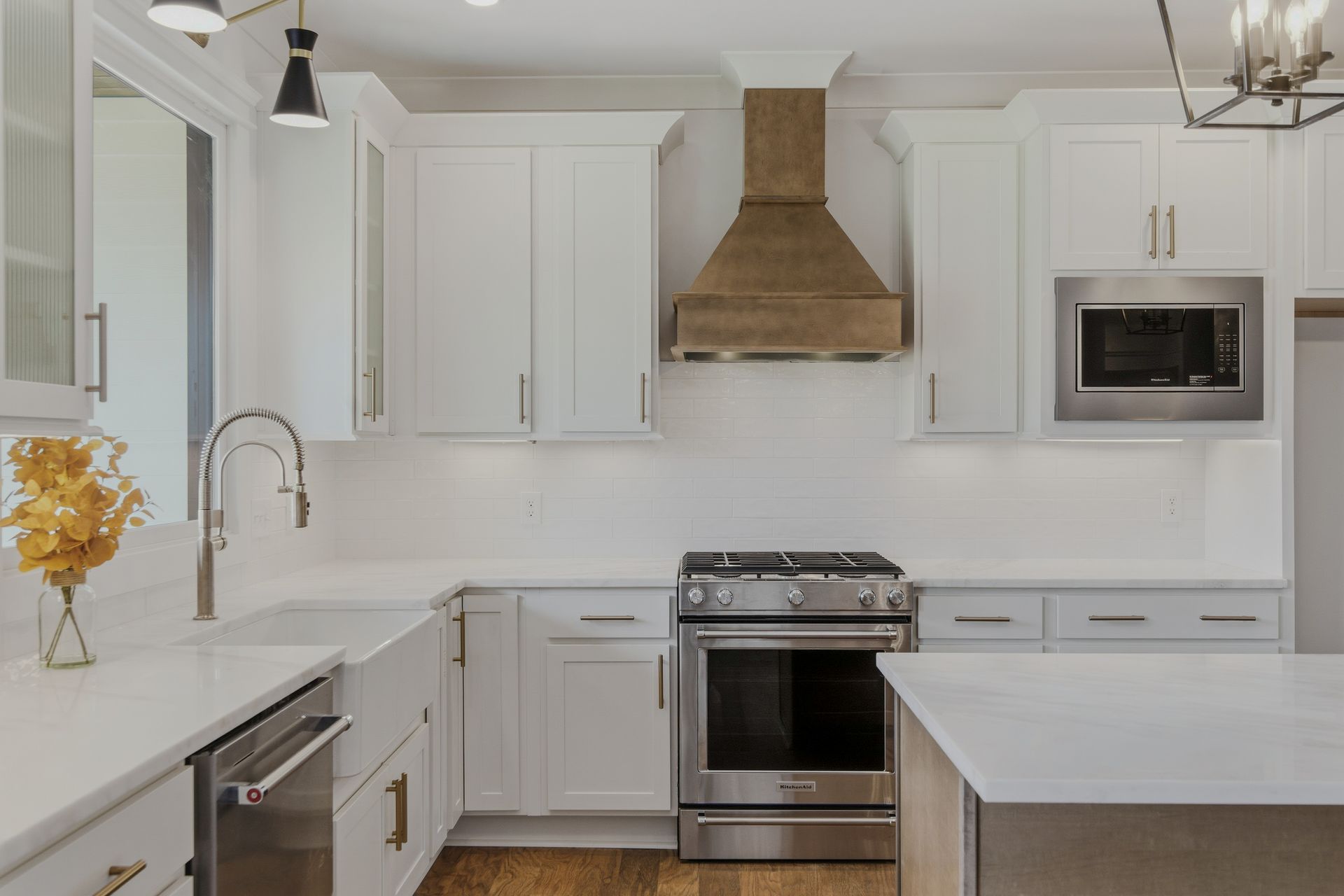 Bright modern white kitchen with stainless steel stove, range hood, and microwave