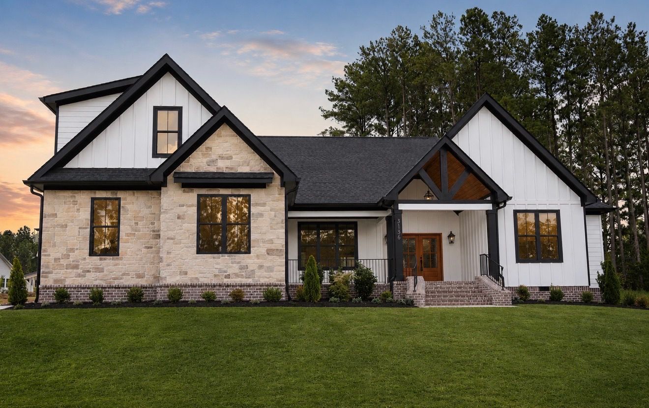 Two-story white house with dark roof and front porch on a grassy lot under a blue sky