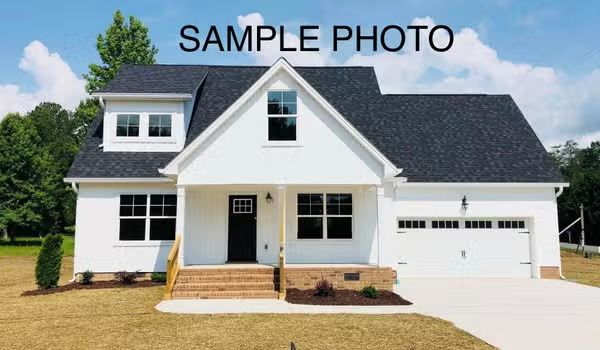 White two-story suburban house with dark roof, front porch, and attached garage under a blue sky