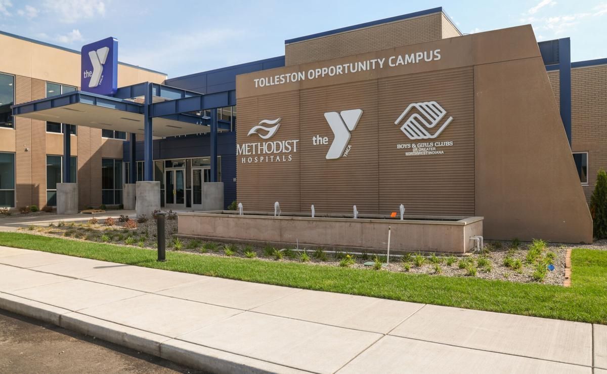 Exterior of a YMCA Opportunity Campus building with tan brick, blue awning, and sidewalk in front