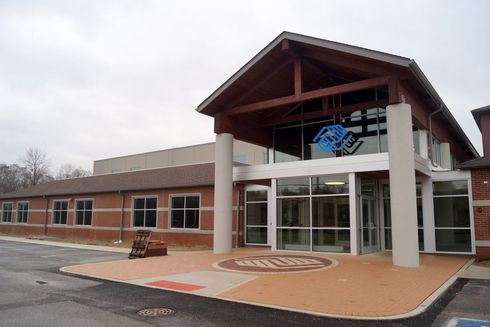 Front entrance of a brick building with glass doors and a peaked roof overhang