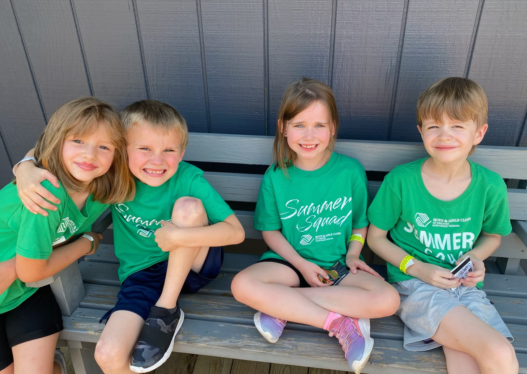 Five smiling children posing together against a white background