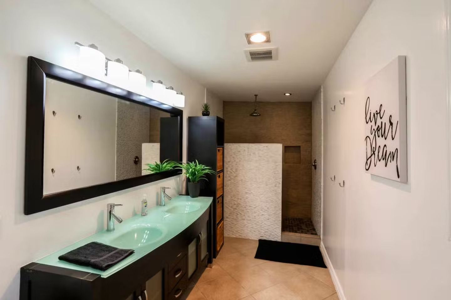 Modern bathroom with double sink vanity, large mirror, and walk-in shower at the far end