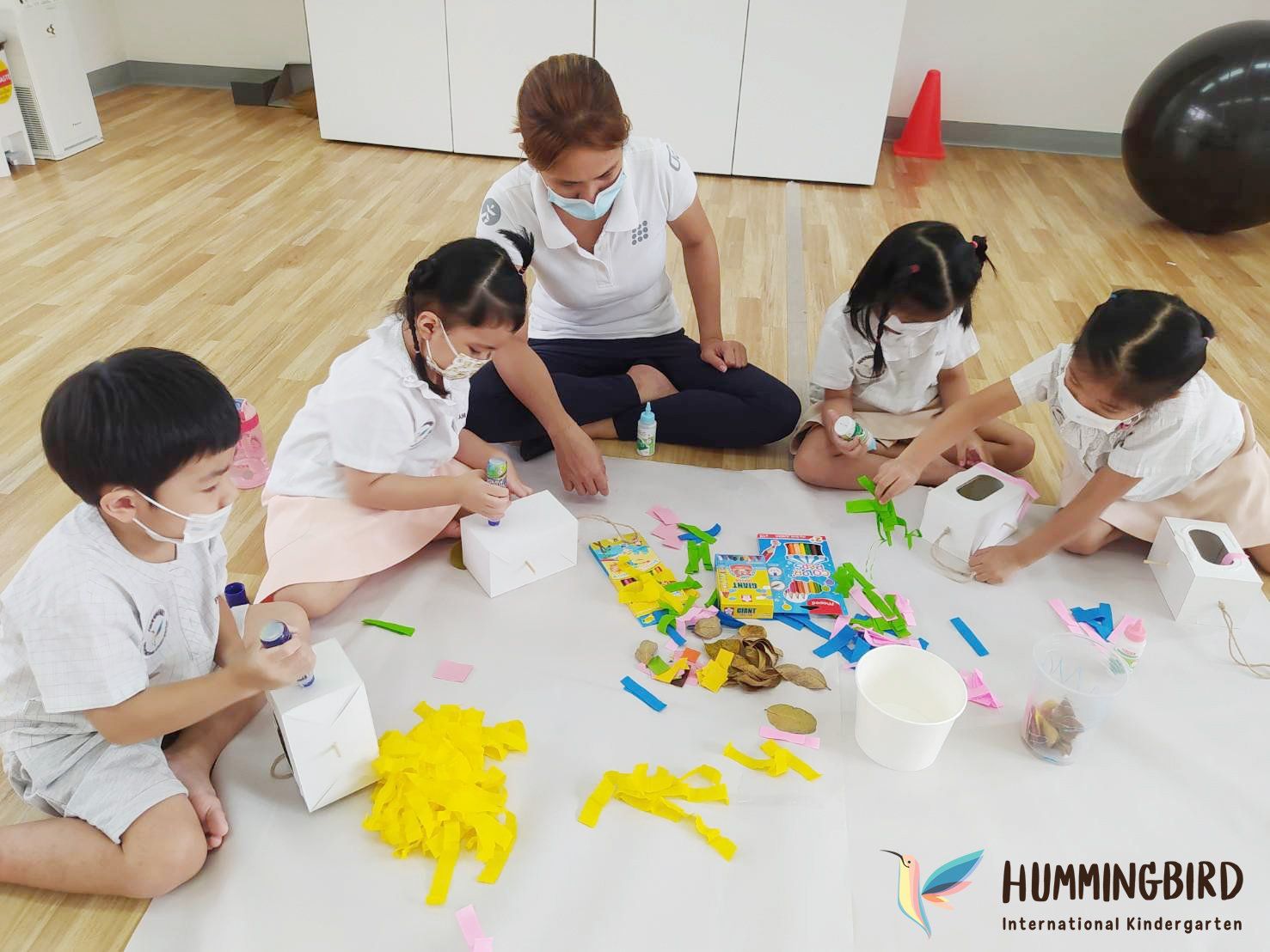 A group of children are sitting on the floor playing with toys.