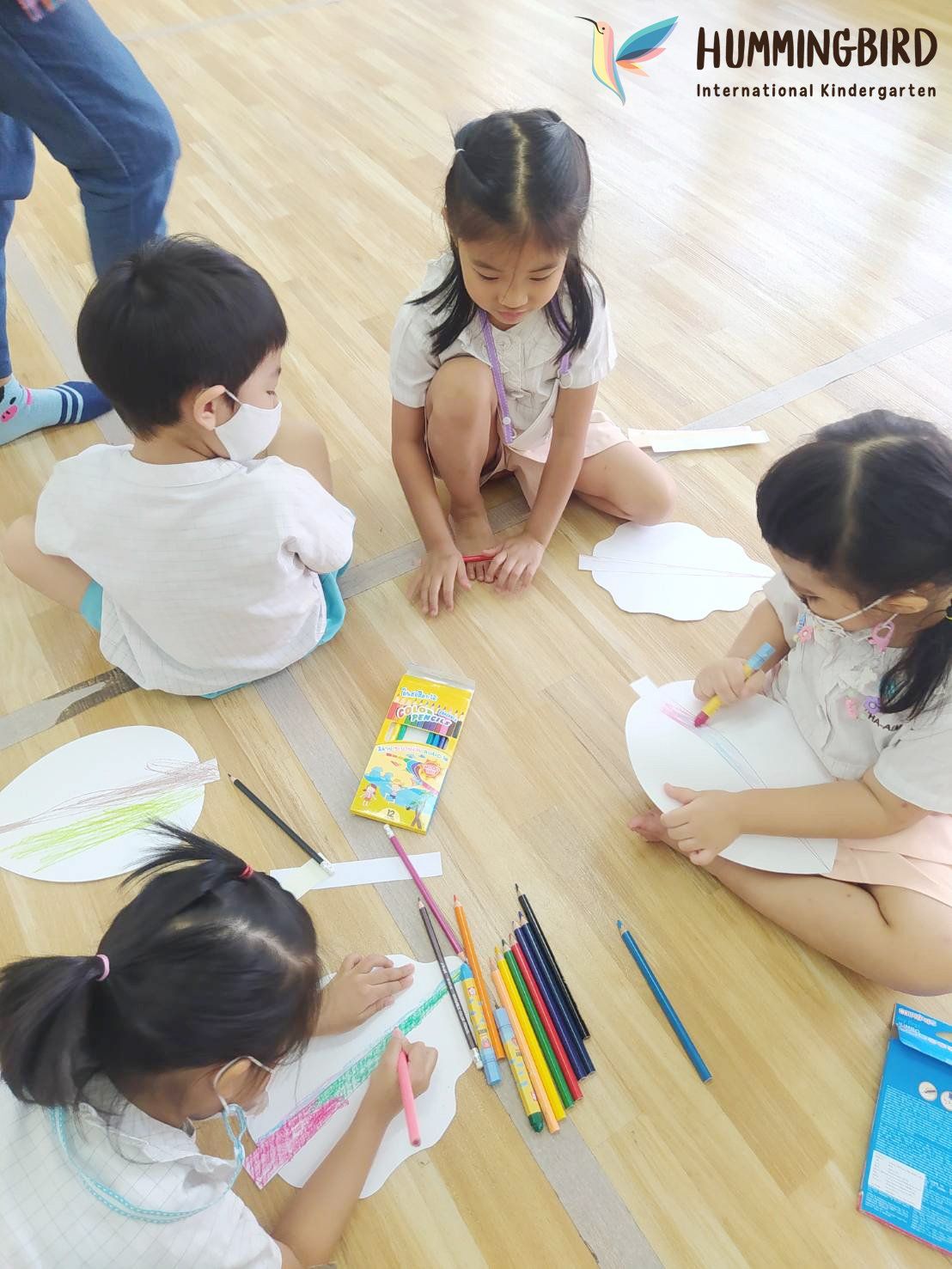 A group of children are sitting on the floor drawing.