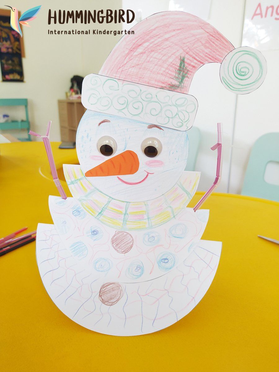 A paper snowman wearing a pink hat and scarf