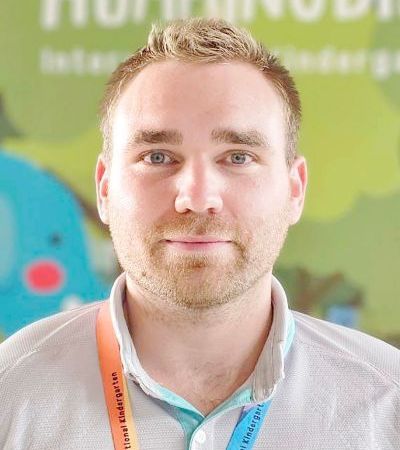A man with a lanyard around his neck is smiling for the camera.