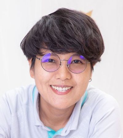 A woman wearing glasses and a white shirt is smiling.