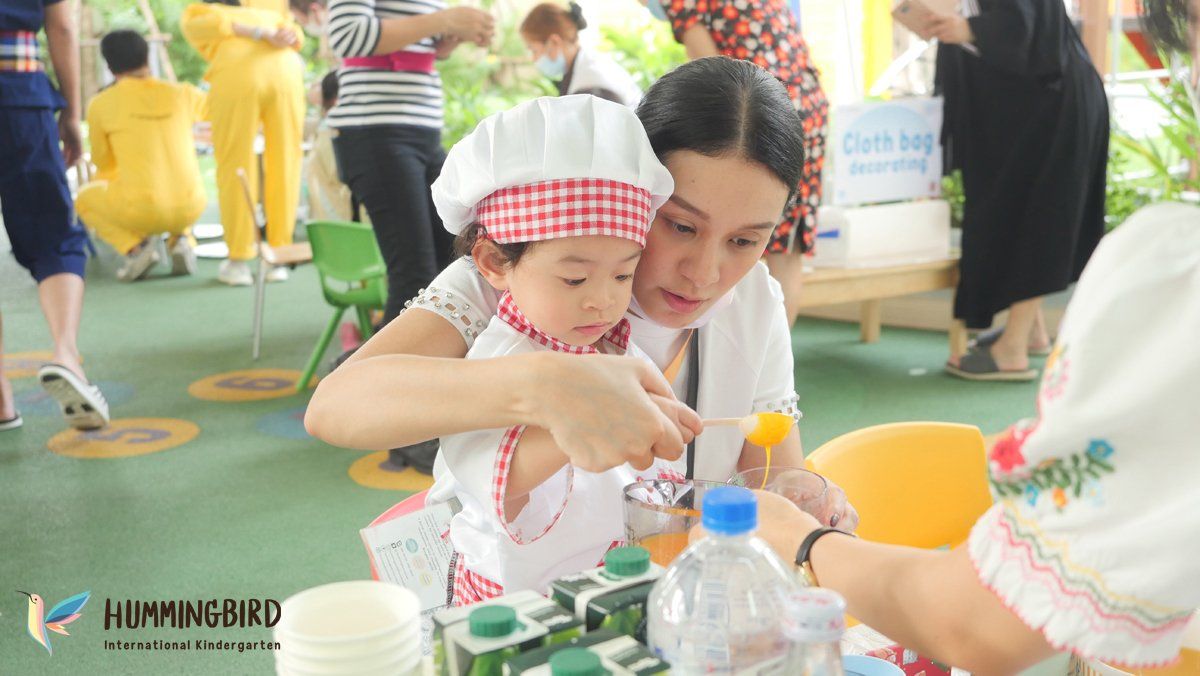 A woman is holding a little girl in a chef 's hat.