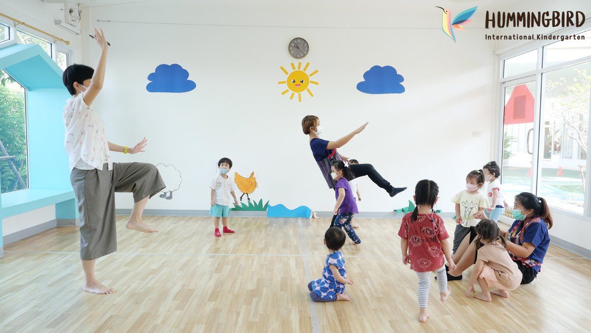 A group of children are playing in a room with a teacher.