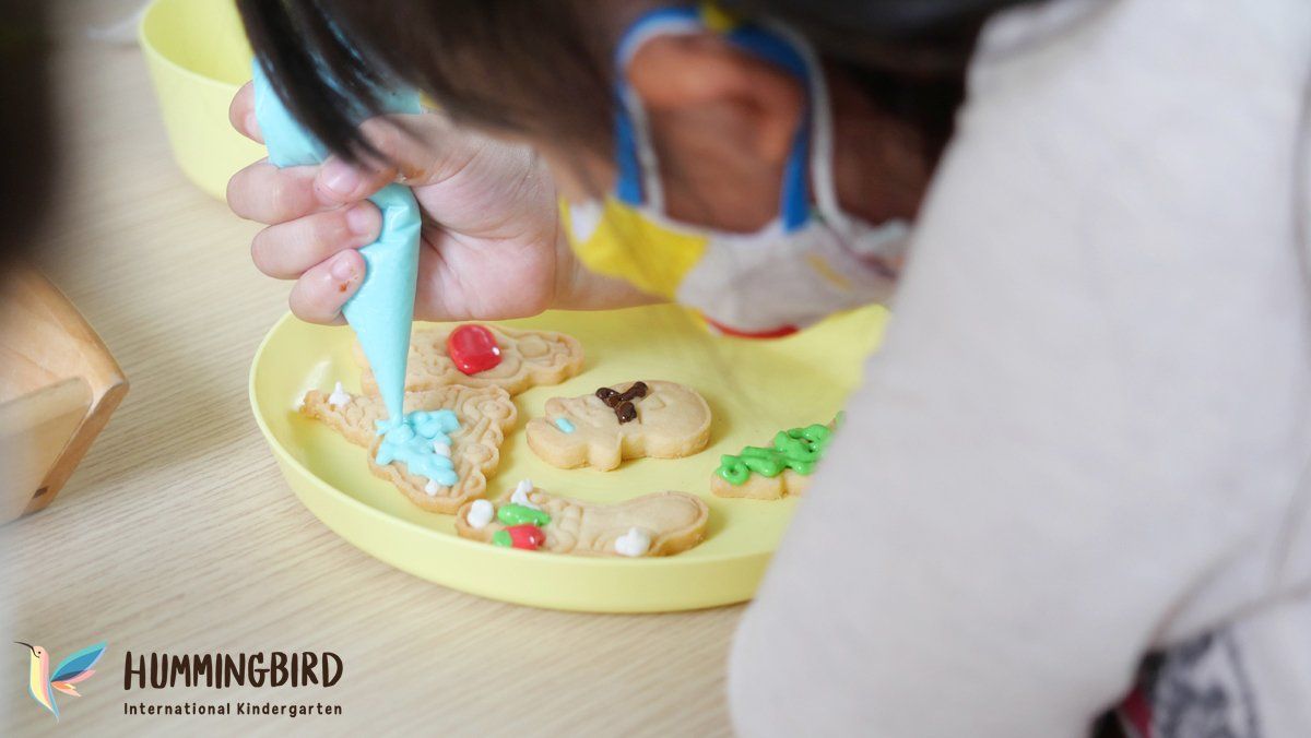 A little girl is decorating gingerbread cookies on a yellow plate.