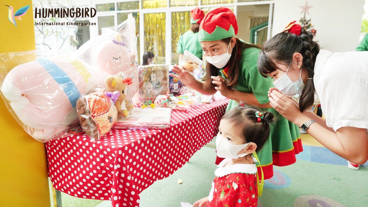 A group of children wearing face masks are standing around a table.