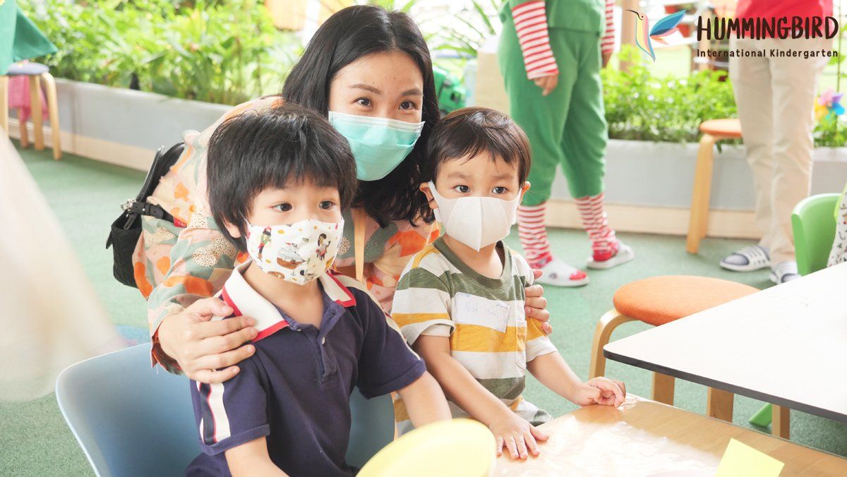 A woman and two children wearing face masks are sitting at a table.