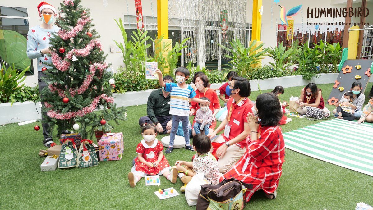 A group of children are sitting in front of a christmas tree.