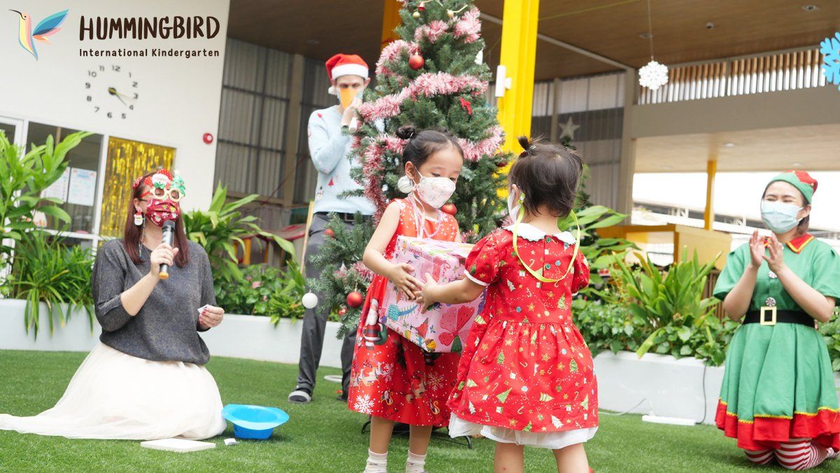 Two little girls are standing next to each other in front of a christmas tree.