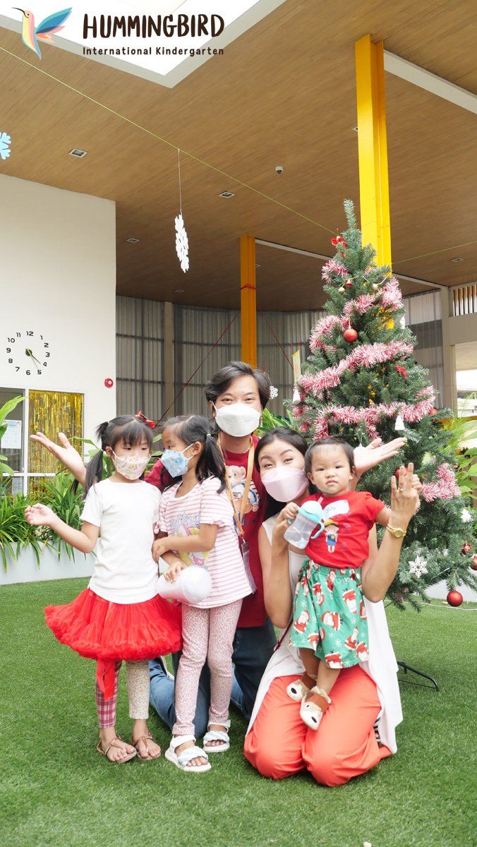 A group of people wearing face masks are posing for a picture in front of a christmas tree.