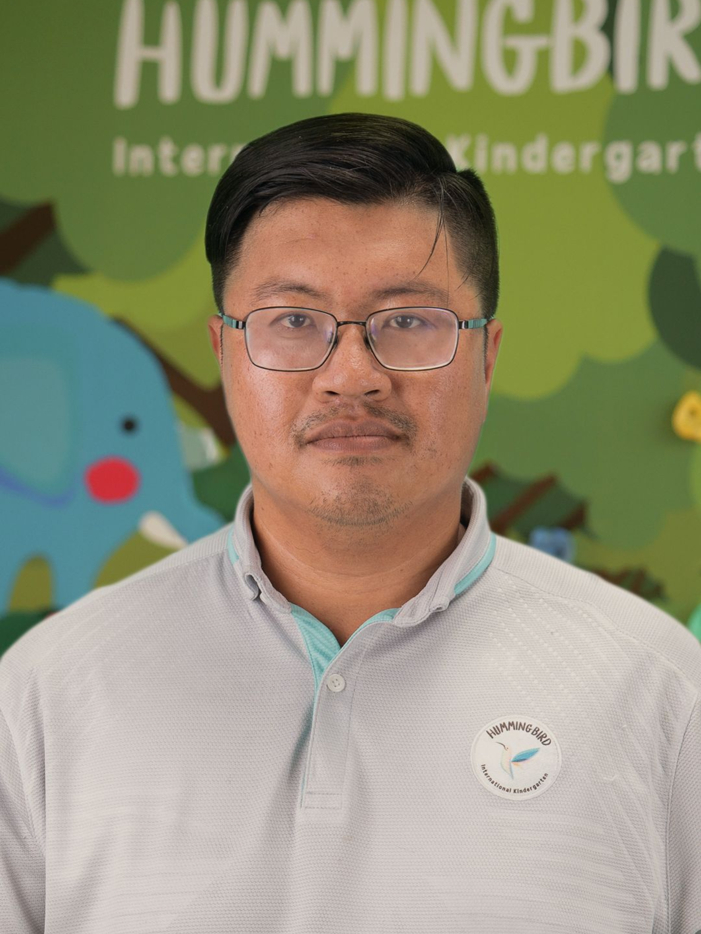 A man wearing glasses and a blue shirt is looking at the camera.