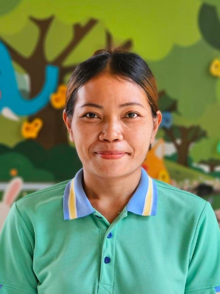 Woman in a green polo shirt smiling in front of a colorful mural.