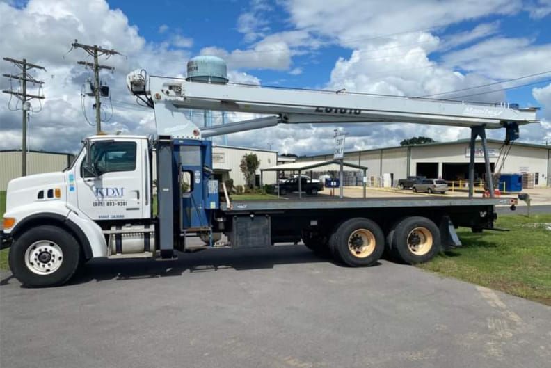 White utility truck with extended boom parked outdoors on a sunny day.