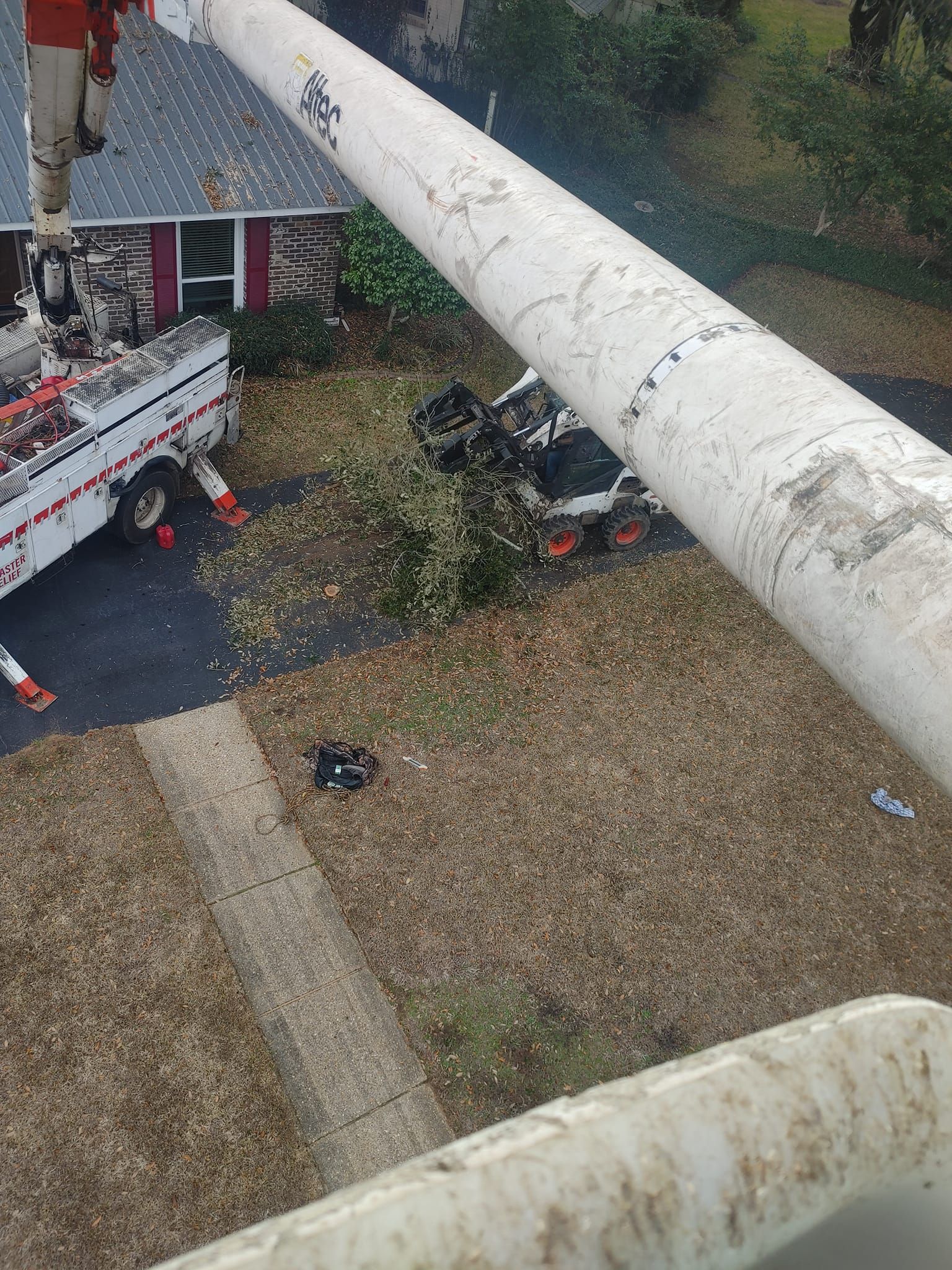 Utility truck near a damaged vehicle; overhead view. Pole in foreground, residential setting.
