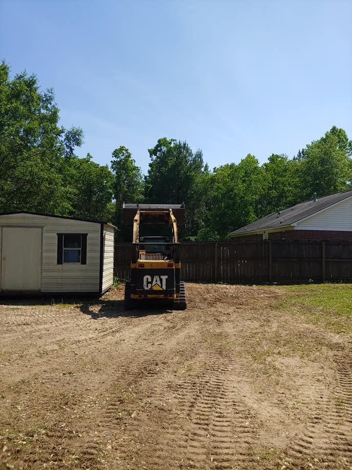 A CAT skid steer loader parked in a dirt yard near a shed and fence on a sunny day.