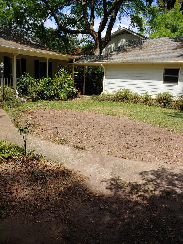 A house with a large bare spot of dirt where grass used to be in front, and a driveway in the foreground.