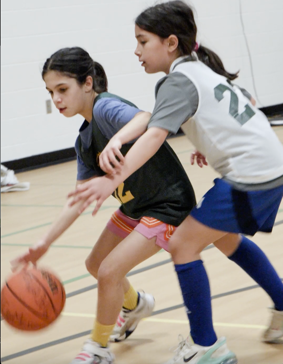 Two basketball players in blue and white jerseys vying for the ball on an indoor court