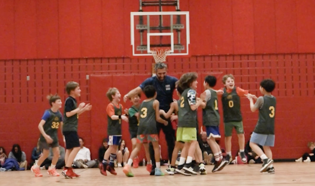 Youth basketball game with players clustered under the hoop in an indoor gym