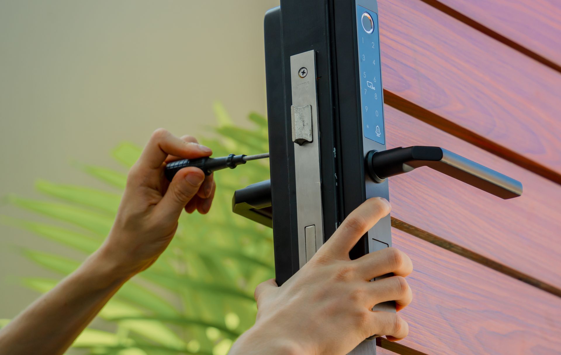 Hands installing a door handle on a black door frame with a screwdriver