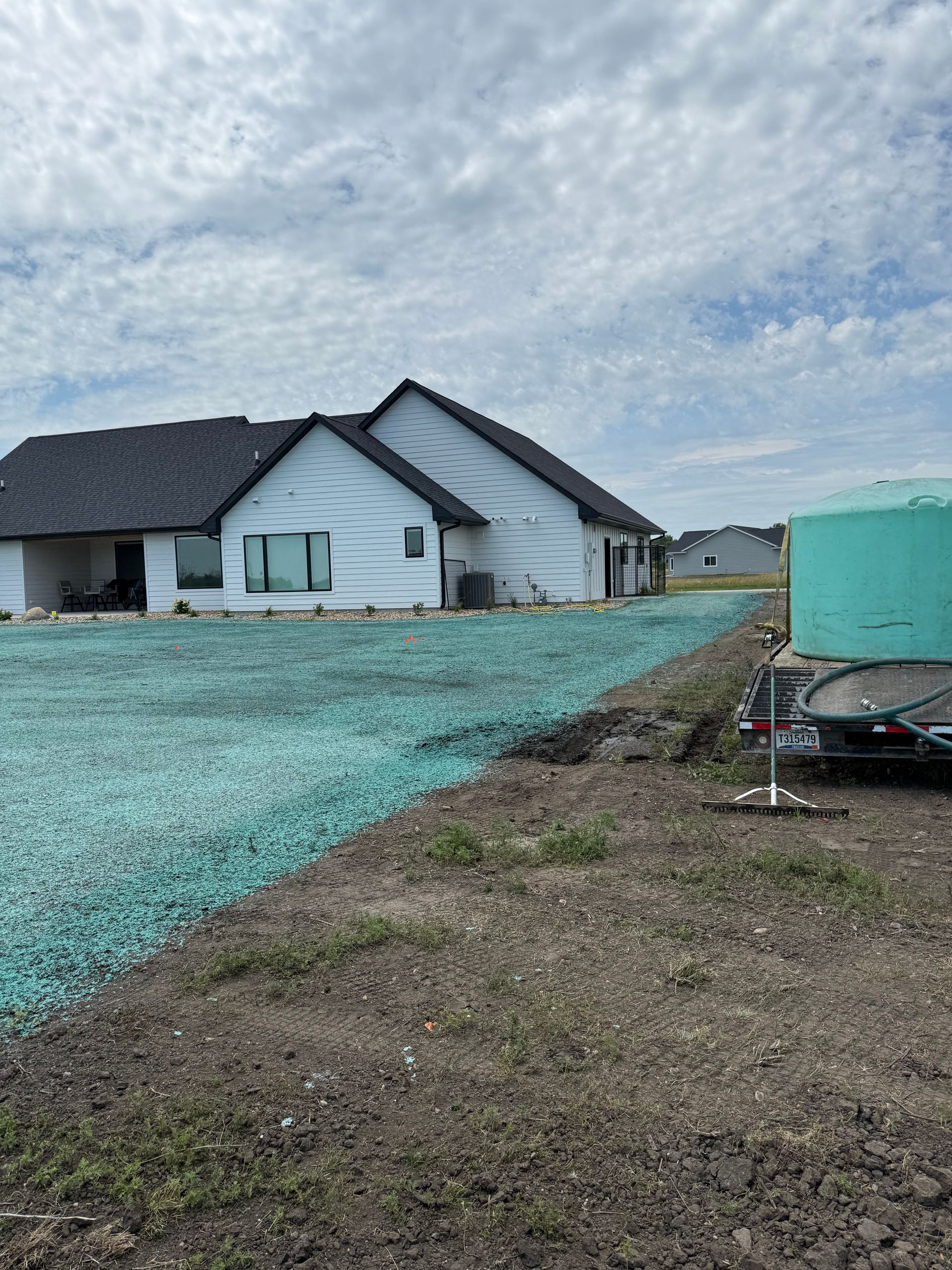 House with new turf; the ground is covered with green seed covering.
