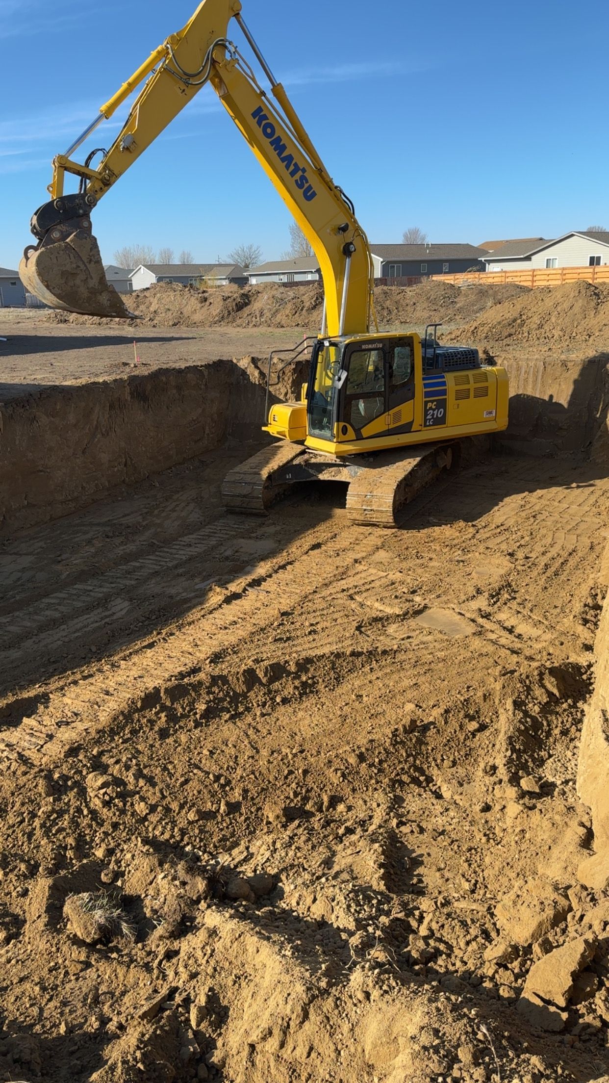 Yellow Komatsu excavator digging earth in a construction site on a sunny day.