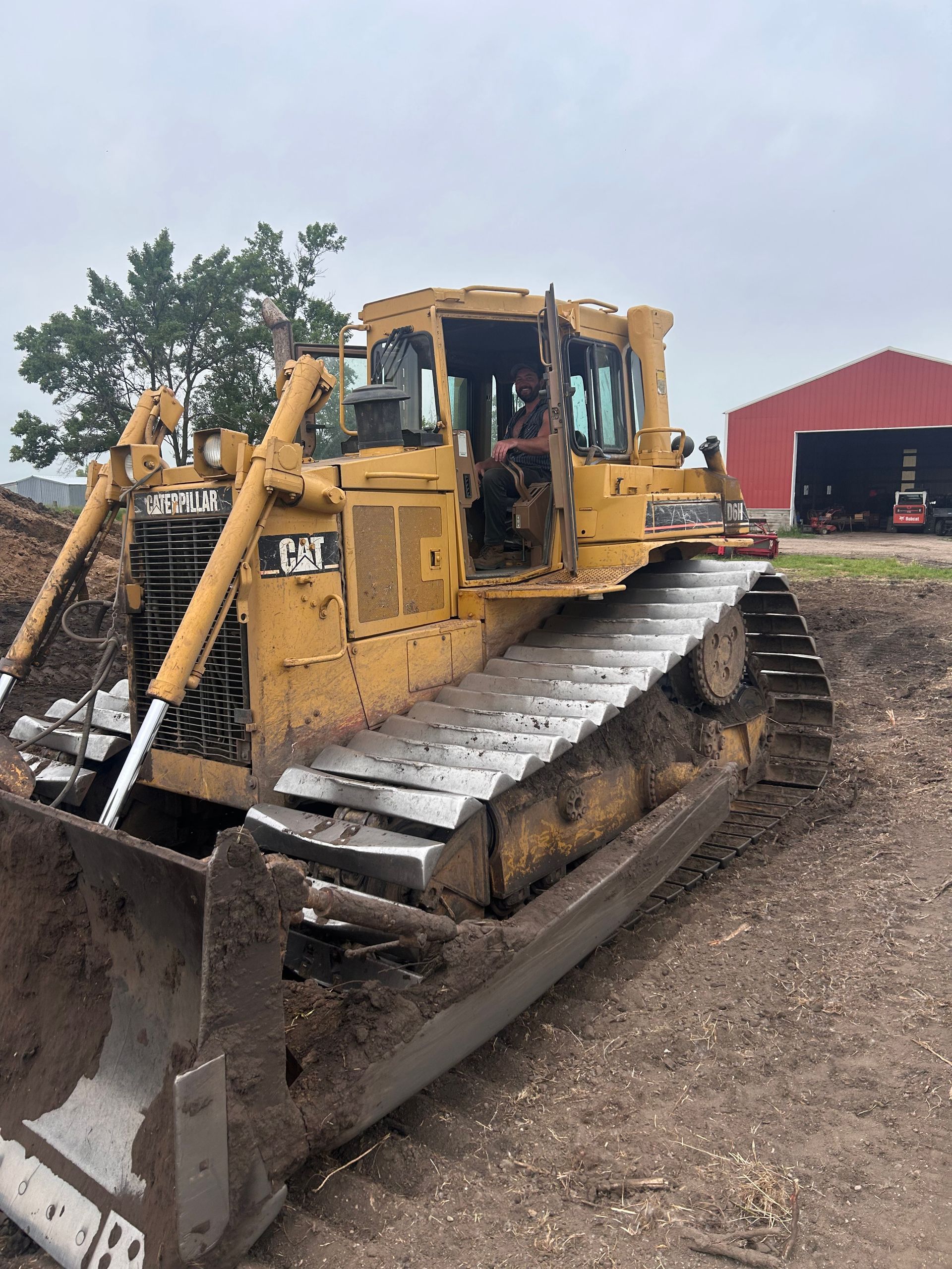 Yellow Caterpillar bulldozer parked outdoors near a red building.